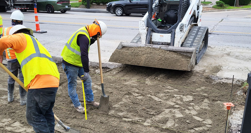 Distributing specialized sand before pouring concrete for a driveway.