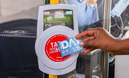 Customer waving their METRO Day Pass at the fare validator upon boarding a METRO curb2curb shuttle.